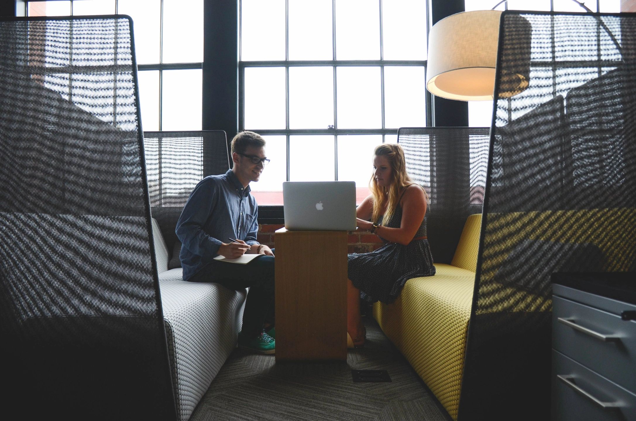 People using a macbook at a desk in a co working space